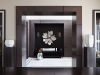 A foyer with custom rift-cut oak wall panels, upholstered fine wool niche panels,  glass and brass wall sconces, luxurious mohair sofa and dramatic Laura Kirar mirror