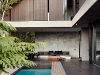 The patio extends seamlessly out from the living area, paved with the same large ceramic tiles used throughout the house. While the pool appears large, its size is exaggerated by the beach entry, which slopes gradually into the water