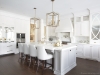 A modern day take on a chic traditional kitchen, complemented by a darker island, gold accents throughout and a mirror inlay integrated fridge section, with three-step crown moulding. Designed, fabricated and installed by NIICO | Photos by Vanessa Galle