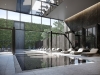 Views through glass screens frame a dramatic water feature that flows into the far end of the pool