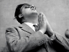 Federico Fellini stands in a prayer-like pose looking towards the heavens. Private Collection