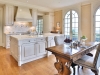 The kitchen features custom built-in millwork and decorative glass display shelving