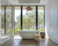 A statement tub and sculptural pendant highlight the primary bathroom, with views of the surrounding landscape | Photo By Kris Tamburello Studios